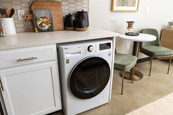 A white washer and dryer in a kitchen with white cabinets and a white counter top